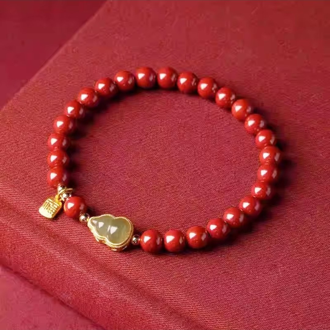 Red bead bracelet with a green stone charm in a gold-tone setting